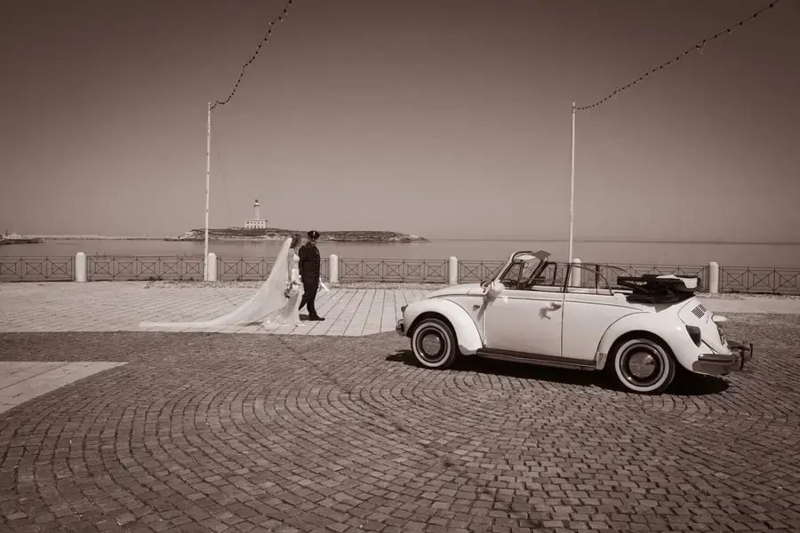 Auto d'epoca bianca sul lungomare con gli sposi